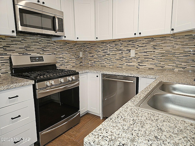 kitchen with sink, stainless steel appliances, dark hardwood / wood-style floors, tasteful backsplash, and white cabinets