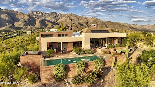 back of property with a mountain view and a patio