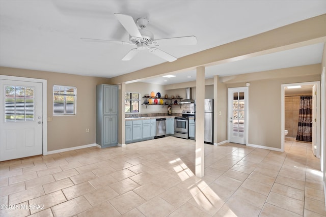 kitchen with appliances with stainless steel finishes, light tile patterned floors, sink, ceiling fan, and wall chimney exhaust hood