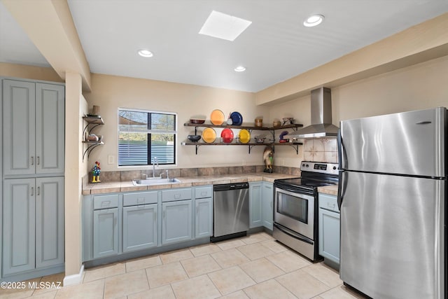 kitchen with sink, light tile patterned floors, ventilation hood, a skylight, and stainless steel appliances