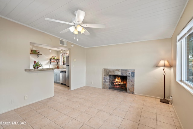 unfurnished living room featuring ceiling fan, crown molding, light tile patterned floors, and a fireplace