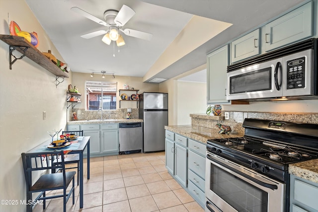 kitchen with vaulted ceiling, ceiling fan, appliances with stainless steel finishes, sink, and light tile patterned floors