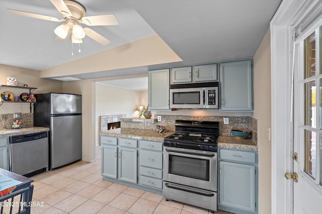 kitchen with ceiling fan, light stone countertops, light tile patterned floors, stainless steel appliances, and lofted ceiling