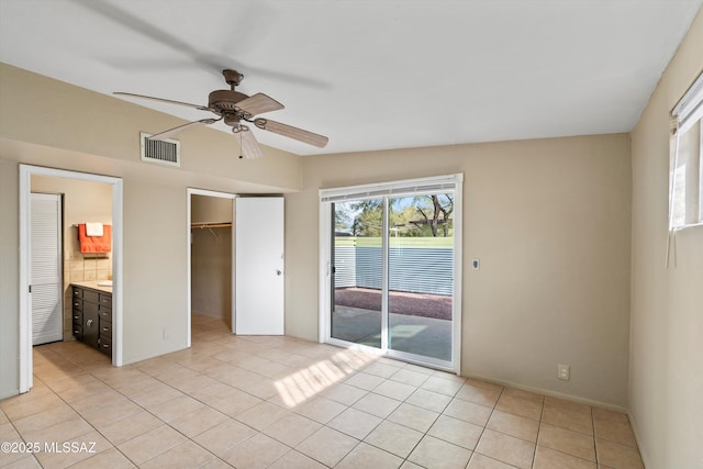 unfurnished bedroom featuring ceiling fan, light tile patterned floors, ensuite bath, a spacious closet, and a closet