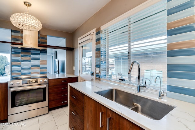 kitchen with hanging light fixtures, electric range, light stone countertops, and sink