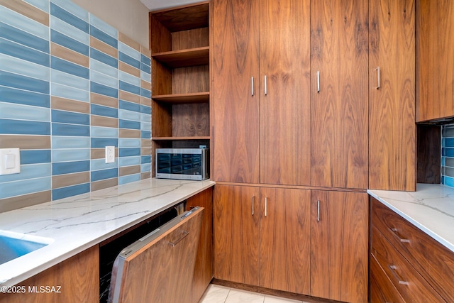 kitchen with backsplash, light tile patterned floors, and light stone countertops