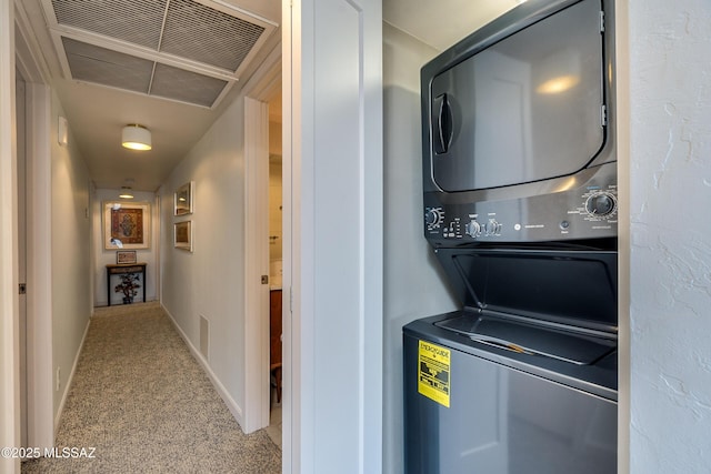 washroom featuring stacked washer and clothes dryer and light carpet