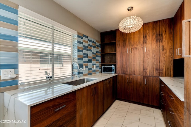 kitchen with sink, an inviting chandelier, light stone counters, pendant lighting, and decorative backsplash