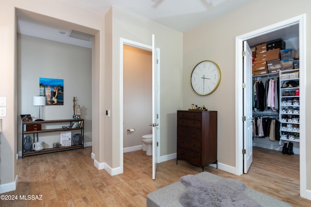 bedroom with light wood-type flooring, ensuite bathroom, and a closet