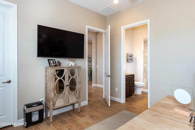 bedroom featuring light wood-type flooring and ensuite bath