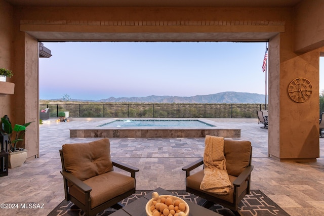 patio terrace at dusk featuring a mountain view and a fenced in pool