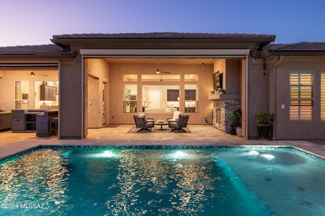 pool at dusk with an outdoor living space, ceiling fan, and a patio area