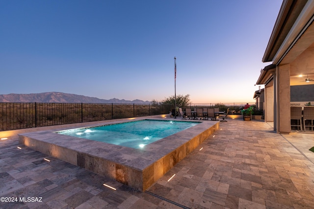 pool at dusk featuring a mountain view, a jacuzzi, and a patio