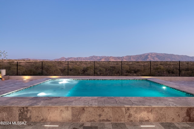 pool at dusk featuring a mountain view