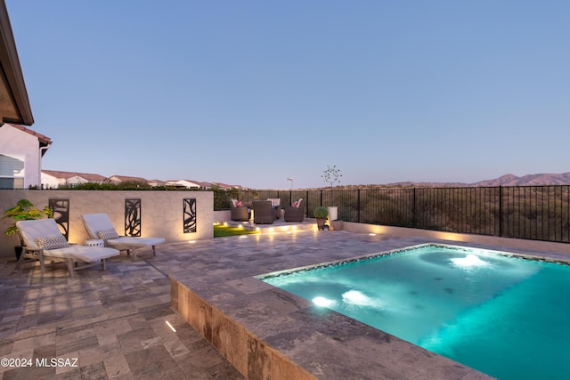 pool at dusk with a mountain view and a patio