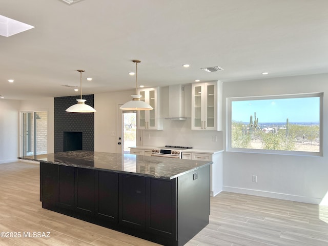 kitchen with visible vents, wall chimney exhaust hood, light wood-style flooring, dark cabinetry, and white cabinetry