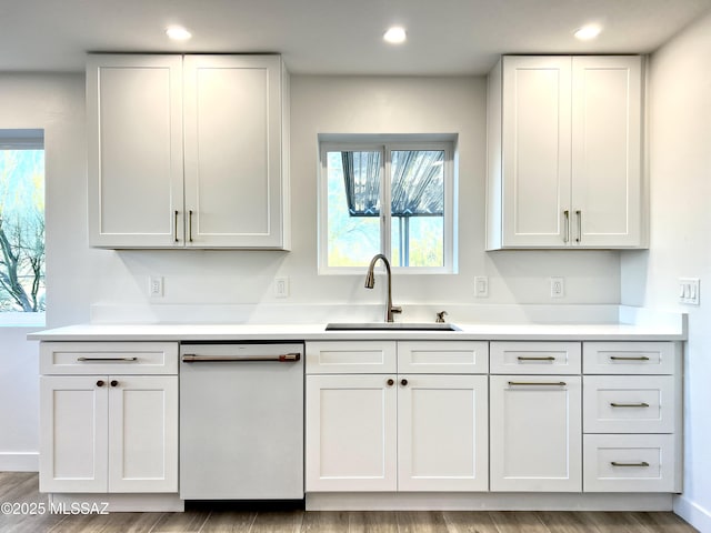 kitchen featuring light countertops, white dishwasher, a sink, and recessed lighting