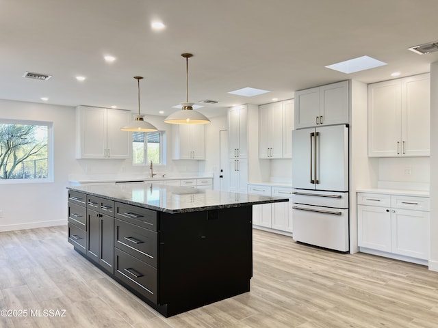 kitchen featuring high end white fridge, a sink, visible vents, and white cabinetry