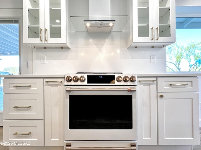 kitchen featuring light countertops, white cabinets, electric range, and extractor fan