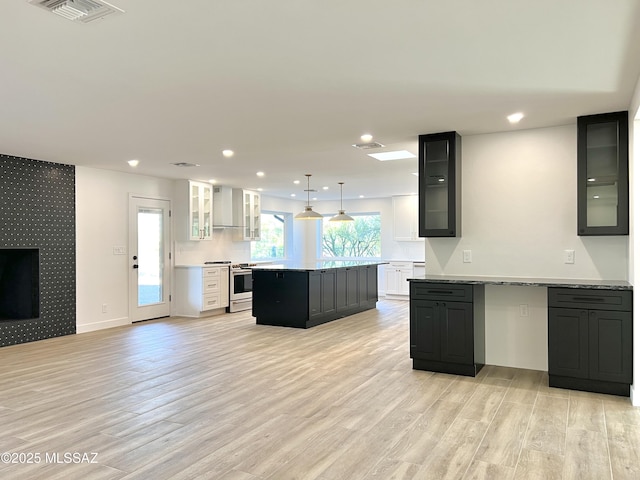 kitchen featuring visible vents, stainless steel range oven, a kitchen island, light wood-type flooring, and wallpapered walls