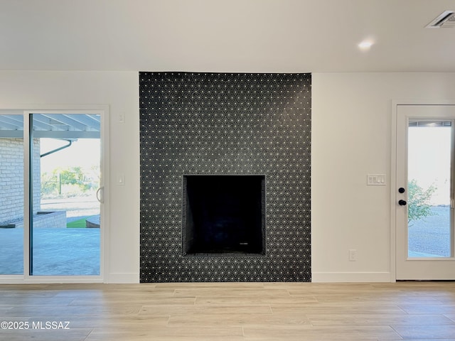 unfurnished living room with wood finished floors, visible vents, and baseboards