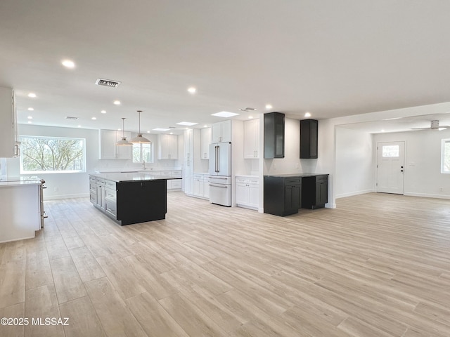 kitchen featuring light wood-style flooring, visible vents, high end fridge, and a center island