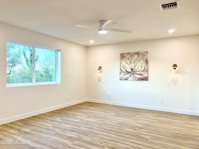 spare room featuring light wood-style floors, visible vents, ceiling fan, and baseboards