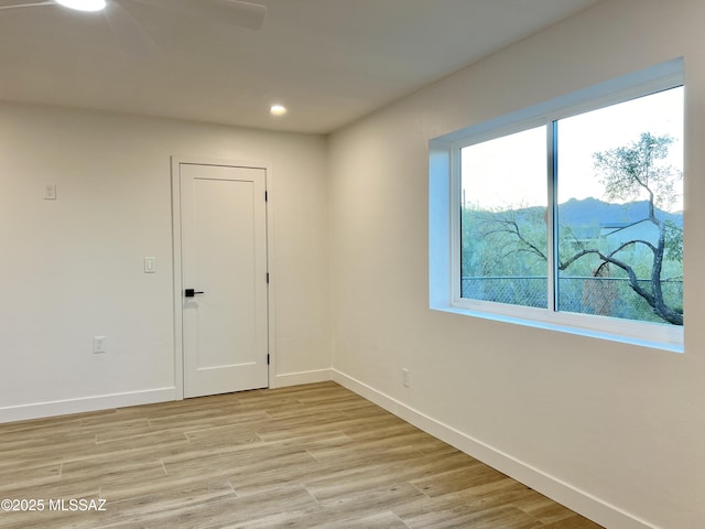 spare room with light wood finished floors, recessed lighting, and baseboards