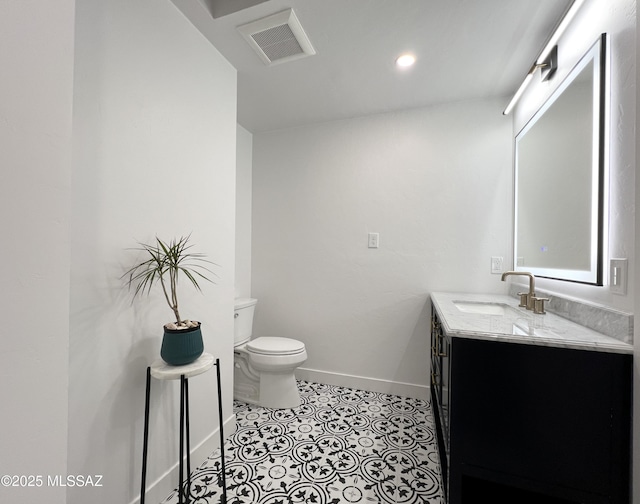 bathroom featuring toilet, vanity, visible vents, baseboards, and tile patterned floors