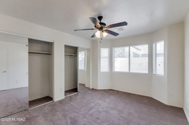 unfurnished bedroom with multiple closets, ceiling fan, and carpet floors