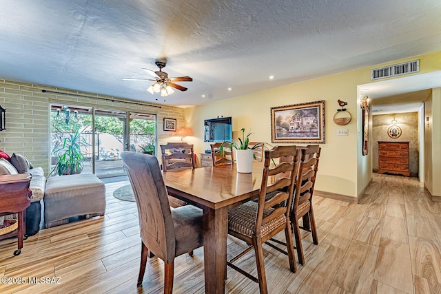 dining space with ceiling fan, light hardwood / wood-style flooring, and a textured ceiling