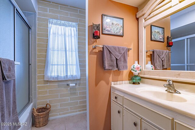 bathroom with bath / shower combo with glass door, vanity, a healthy amount of sunlight, and tile patterned flooring