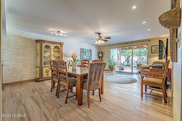 dining area with ceiling fan and brick wall