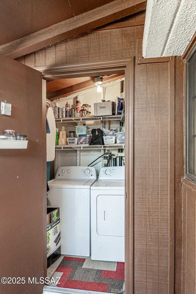 laundry room with wood walls and independent washer and dryer