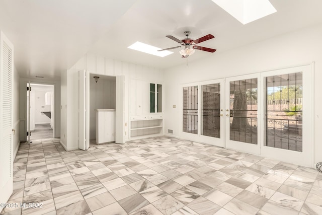 interior space featuring ceiling fan, french doors, and a skylight