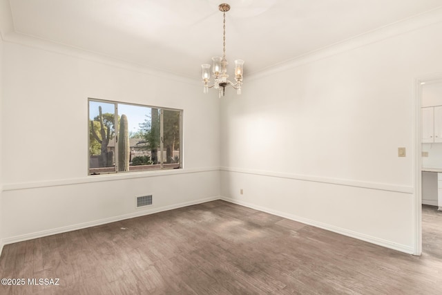 spare room with an inviting chandelier, ornamental molding, and dark hardwood / wood-style flooring