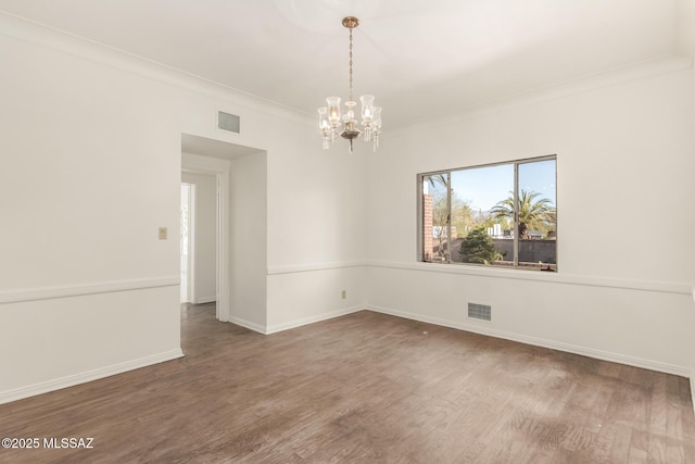 unfurnished room featuring an inviting chandelier, crown molding, and wood-type flooring