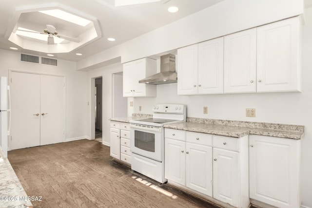 kitchen featuring white appliances, wall chimney range hood, ceiling fan, and white cabinetry