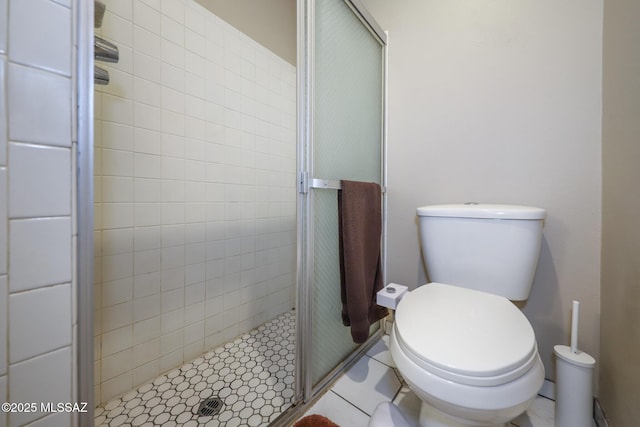 bathroom featuring toilet and a shower with shower door