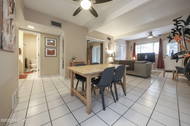 tiled dining space with ceiling fan and beam ceiling