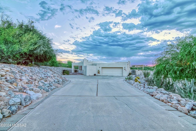 view of front of home featuring a garage, concrete driveway, and stucco siding