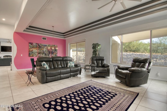 tiled living area with visible vents, a raised ceiling, and a ceiling fan