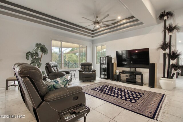 tiled living area featuring a tray ceiling and a ceiling fan