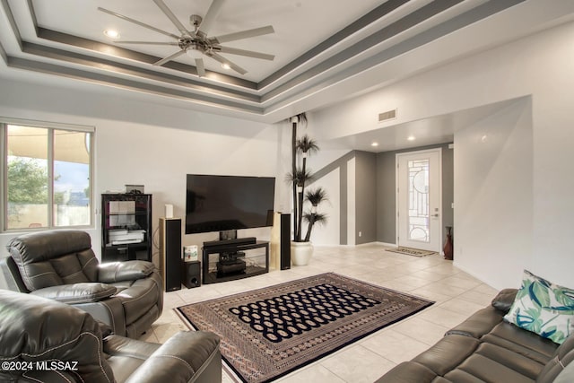 living area featuring light tile patterned floors, a raised ceiling, visible vents, and a ceiling fan