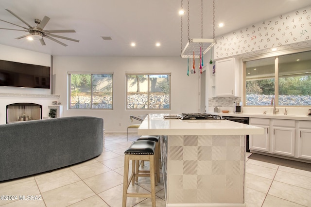 kitchen with light tile patterned floors, a fireplace, white cabinetry, and open floor plan