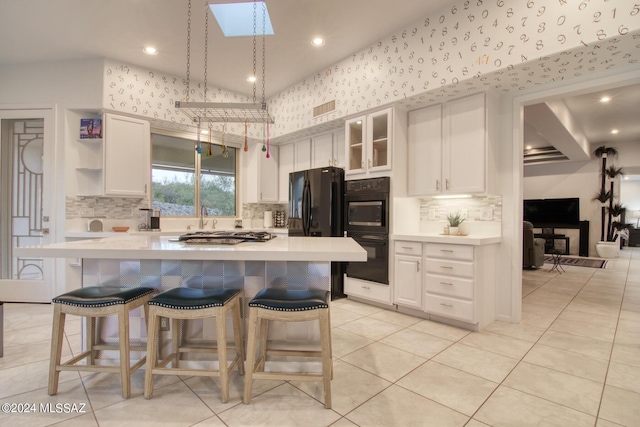 kitchen with visible vents, light countertops, a kitchen bar, and white cabinetry