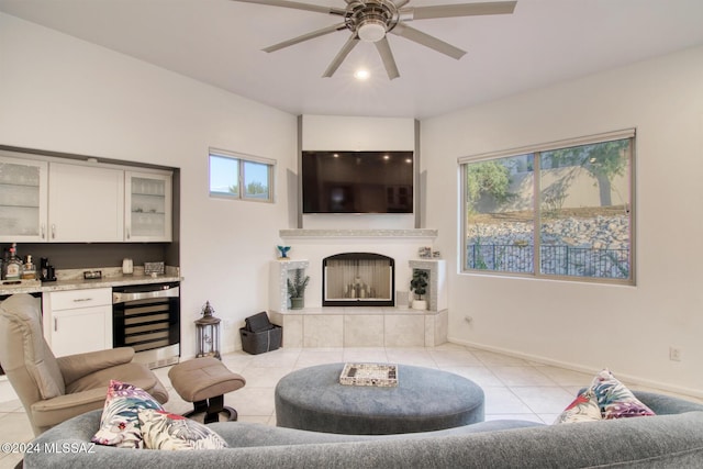 living area featuring light tile patterned flooring, beverage cooler, a fireplace, baseboards, and a bar