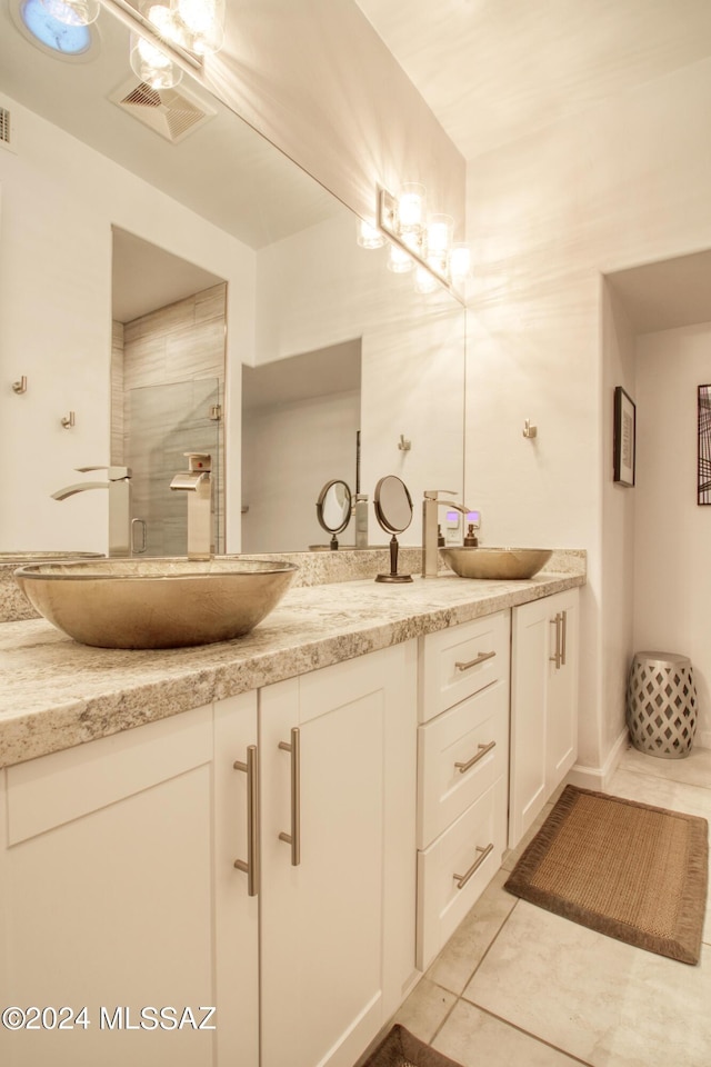 full bathroom with visible vents, double vanity, a sink, and a shower with door