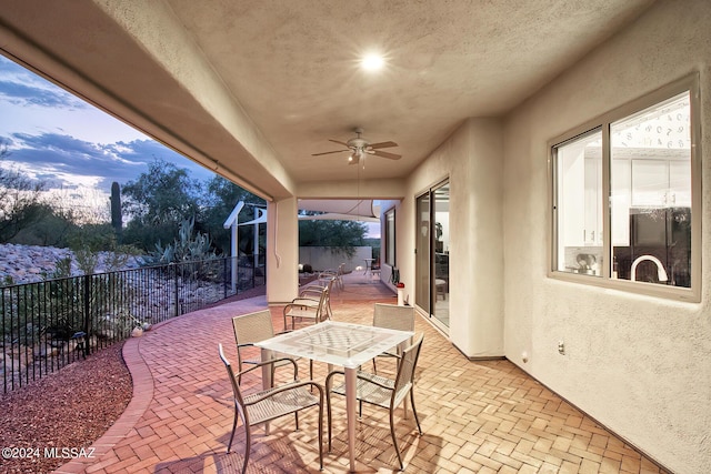 view of patio with outdoor dining space, ceiling fan, and fence