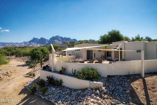 rear view of property featuring a fenced front yard, a mountain view, and stucco siding